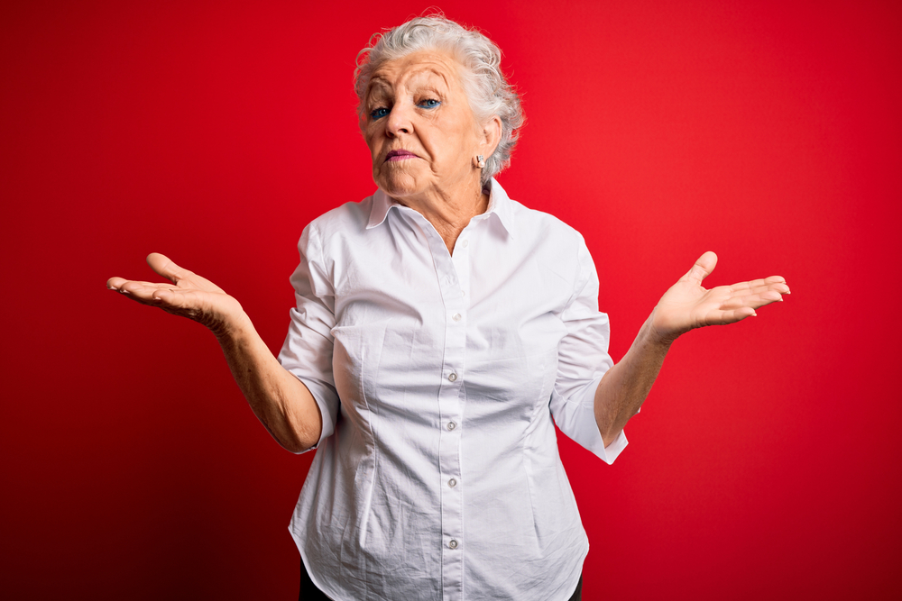 Senior woman holds up both palms as if weighing options.